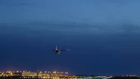 Small-propeller-plane-flying-against-blue-hour-sky,-landing-on-airport-runway