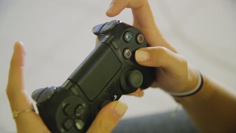 Closeup-of-female-hands-actively-using-black-PS4-dualshock-controller-to-play-game-inside-home-interior