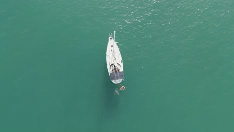 Ein-Segelboot-Im-Meer-Mit-Menschen,-Die-Darum-Herum-Schwimmen-Luftbild-Von-Oben