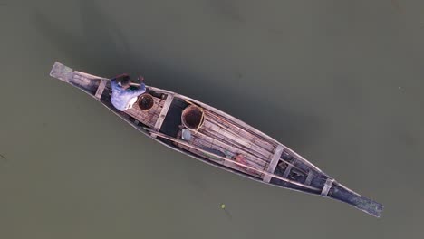 Aerial-View-Of-Lone-Fisherman-On-Traditional-Wooden-Boat-Floating-Line-Fishing