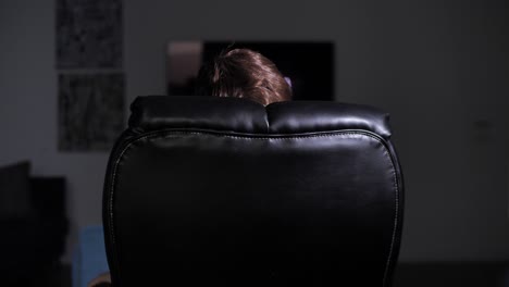 Rear-view-of-unrecognizable-person-sitting-in-armchair-in-dark-office