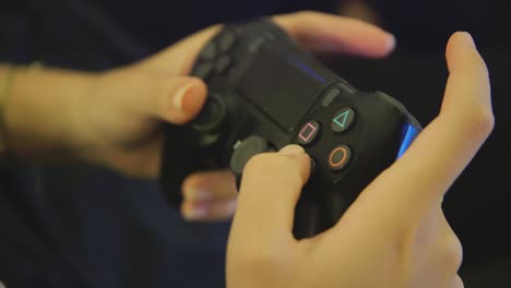 Closeup-of-female-hands-using-black-PS4-dualshock-controller-to-play-game-inside-home