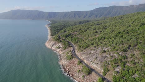 Coastal-Road-With-Vehicle-Driving-Along-The-Coral-Sea-Near-The-Wangetti-In-Australia---aerial-drone-shot