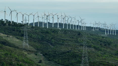Strommasten-Und-Nachhaltige-Windturbinen,-Die-Sich-Auf-üppig-Grünen-Hügeln-Drehen