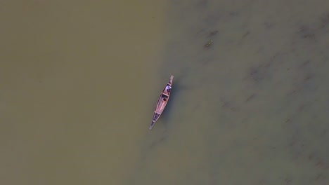 Aerial-View-Of-Lone-Fisherman-On-Traditional-Wooden-Boat-On-River