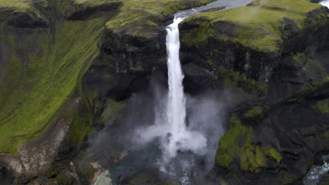 Aerial-circle-panning-tracking-shot-of-the-astonishing-Haifoss-waterfall-in-the-mountain-gorge-of-Fossárdalur,-in-Iceland
