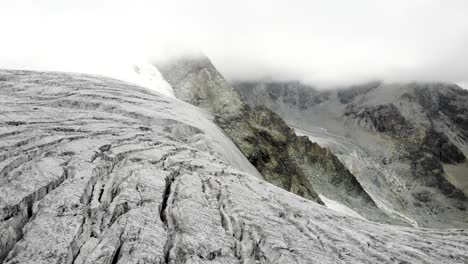 Schwenken-Der-Luftaufnahme-In-Richtung-Der-Gletscherspalten-Am-Rand-Des-Moiry-Gletschers-Bei-Grimentz-Im-Wallis,-Schweiz,-Mit-Blick-Auf-Die-Gletscherzunge-Und-Den-See-Im-Tal
