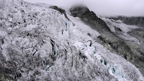Luftüberführung-über-Einen-Wanderer-An-Einem-Aussichtspunkt-Des-Moiry-gletschers-Bei-Grimentz-Im-Wallis,-Schweiz,-Mit-Blick-Auf-Die-Eisspalten,-Während-Sich-Die-Berge-In-Den-Wolken-Verstecken