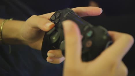 Closeup-of-female-hands-using-black-PS4-dualshock-controller,-spamming-buttons-to-play-game-inside-home