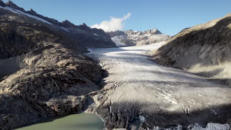 Aerial-view-of-Rhone-glacier-near-Furka-mountain-pass-at-the-border-of-Valais-and-Uri-in-Switzerland-with-a-pan-down-from-the-ice-to-glacial-lake