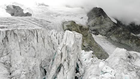 Aerial-flyover-through-the-ice-crevasses-of-the-Moiry-glacier-near-Grimentz-in-Valais,-Switzerland-with-on-a-cloudy-summer-afternoon