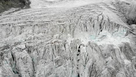 Aerial-flyover-over-the-Moiry-glacier-near-Grimentz-in-Valais,-Switzerland-with-a-pan-up-from-the-icy-crevasses