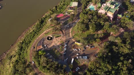 Eine-Dynamische-Orbitale-Luftaufnahme-Der-öffentlichen-Straße,-Die-Um-Das-Von-Bäumen-Und-Einigen-Nachbarhäusern-Umgebene-Haus-In-Der-Nähe-Des-Iguazu-flusses-Bei-Sonnenuntergang-Führt