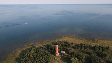 Descending-panorama-aerial-drone-flight-over-lost-place-lighthouse-at-the-coast-of-baltic-sea---country-side-of-Estonia-in-Europe---nature-helicopter-flyover-establishing-shot-summer-2022---bird-view