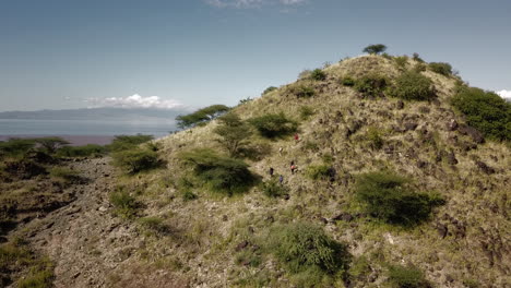 Vista-De-Dron-De-4k-De-Un-Grupo-De-Turistas-De-Senderismo-Escalando-Una-Montaña-Verde-En-El-Este-De-África