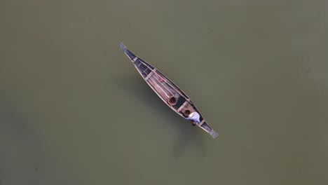Aerial-Looking-Down-View-Of-Lone-Fisherman-On-Traditional-Wooden-Boat-Floating-On-The-Ichamati-River