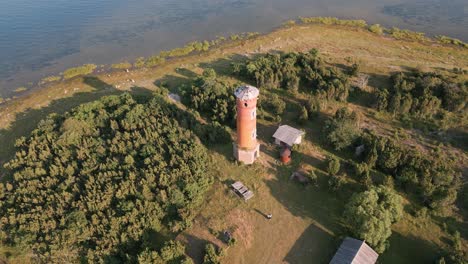 Fly-away-from-place-lighthouse-at-the-coast-of-baltic-sea---country-side-of-Estonia-in-Europe---nature-helicopter-flyover-establishing-shot-summer-2022---bird-view---aerial-drone