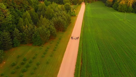 Group-of-friends-waking-peacefully-along-a-dirt-rural-road-next-to-a-forest-at-sunset
