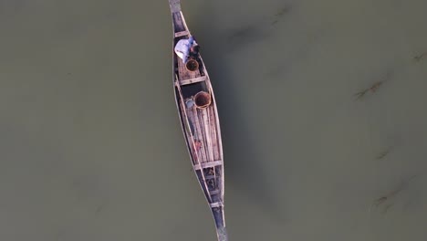Aerial-Overhead-View-Of-Lone-Fisherman-On-Traditional-Wooden-Boat-Floating-On-The-Ichamati-River
