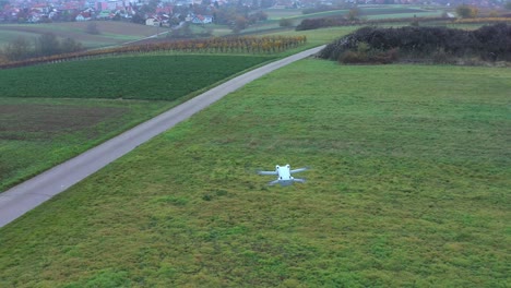 Drone-Quadcopter-Blanco-Flotando-Sobre-Un-Hermoso-Campo-De-Hierba-En-Un-Día-Soleado