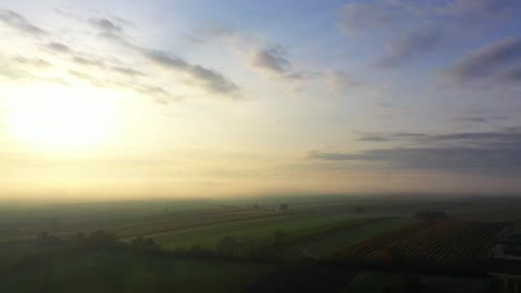 Misty-Sunrise-Over-Rural-Landscape-With-Wind-Turbines-At-The-Background