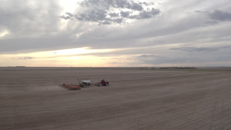 A-Seeder-Tractor-Seeding-At-The-Farmland-Against-Dramatic-Sky-In-Saskatchewan,-Canada