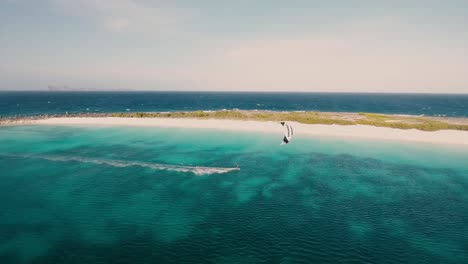 Man-doing-speed-kiteboard-along-caribbean-white-sand-beach,-aerial-view-Los-Roques