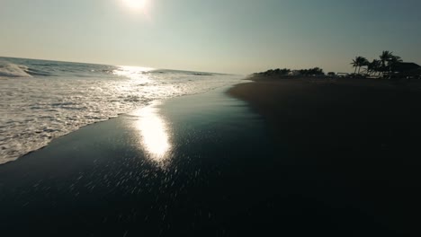Flying-Over-Black-Sand-Beach-With-Waves-Splashing-In-Monterrico,-Guatemala