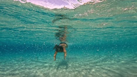 Underwater-scene-of-brunette-caucasian-woman-swimming-in-incredible-crystal-clear-tropical-sea-water-of-exotic-island