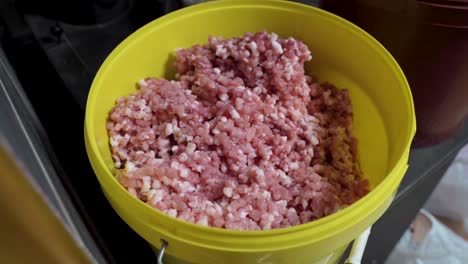 Full-bucket-of-minced-fresh-pork-meat,-close-up-motion-back-view