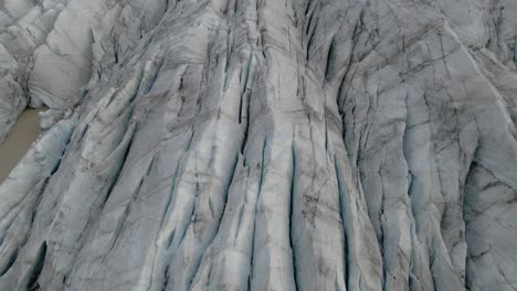 Tilt-up-from-Cracked-ice-pattern-revealing-impressive-Svinafellsjokull-Glacier-Landscape,-Aerial-Pullback