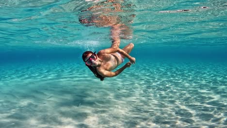 Beautiful-Underwater-scene-of-little-redhead-girl-swimming-immersed-in-shallow-crystal-clear-pristine-tropical-seawater-of-exotic-island