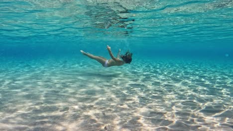Underwater-footage-of-little-girl-swimming-immersed-in-crystal-clear-pristine-tropical-seawater-of-exotic-island