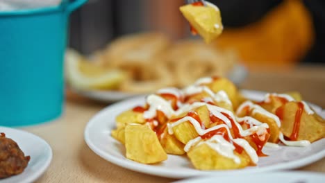 Close-up-on-typical-Spanish-dish-"Patatas-Bravas",-fork-rise-a-roasted-potatoes-with-ketchup-and-mayonnaise-on-it