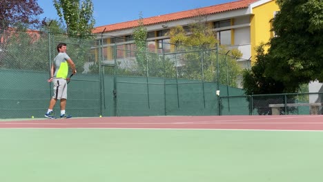 Fit-young-man-in-sportswear-playing-tennis-on-hard-court-on-a-sunny-day