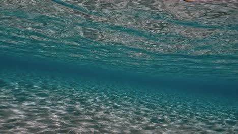 Authentic-underwater-scene-of-crystalline-turquoise-tropical-sea-water-with-rippled-surface-and-reflections-on-seabed-with-blue-background