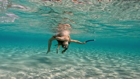 Underwater-scene-of-cute-young-girl-with-divng-mask-and-holding-snorkel-having-fun-floating-in-crystalline-pure-tropical-sea-water-of-exotic-island