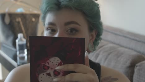 Green-haired-woman-looking-at-the-small-mirror-she-holds-in-her-hand-to-see-if-her-makeup-is-good