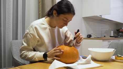 close-up-shot-of-a-young-woman-carving-orange-pumpkin-at-home-for-the-Halloween