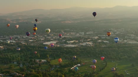 Aerial-shot-of-air-balloons-with-layers-of-lush-green-land-off-in-the-background