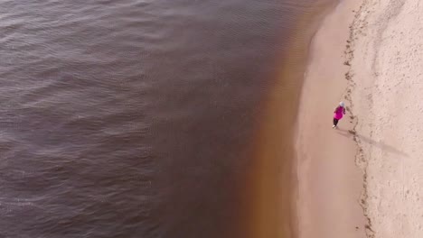 Joggerin-Läuft-An-Der-Küste-Am-Weißen-Sandstrand-In-Europa,-Luftaufnahme