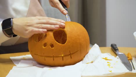 close-up-sliding-shot-of-a-young-woman-carving-orange-pumpkin-at-home-for-the-Halloween-decoration