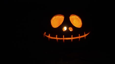 close-up-sliding-shot-of-a-carved-orange-pumpkin-with-light-candle-inside-in-the-dark-for-the-Halloween-decoration