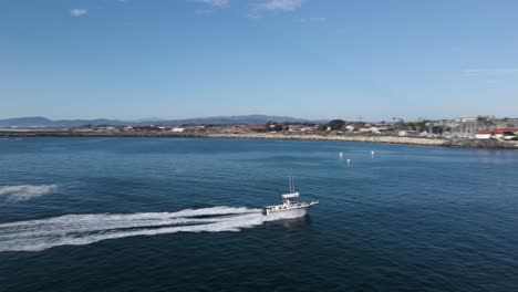 aerial-view-of-boat-driving-into-oceanside-harbor-at-full-speed