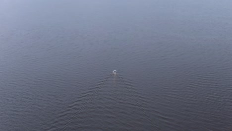 Aerial-view-of-small-boat-in-a-lake,-splitting-waves