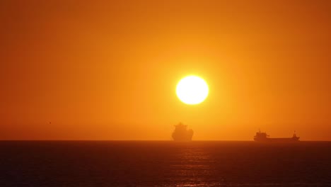 Time-lapse-of-the-sun-setting-over-the-ocean-between-two-big-ships-in-Europe