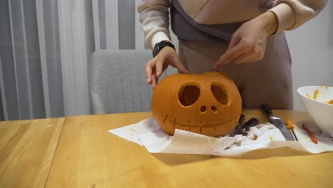 close-up-sliding-shot-of-a-young-woman-carving-orange-pumpkin-at-home-for-the-Halloween-decoration,-she-is-cleaning-pumpkin-from-the-seeds