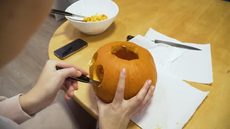 close-up-shot-of-a-woman-carving-orange-pumpkin-at-home-for-the-Halloween