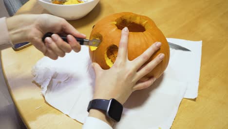 close-up-shot-of-a-woman-carving-orange-pumpkin-at-home-for-the-Halloween-in-4k