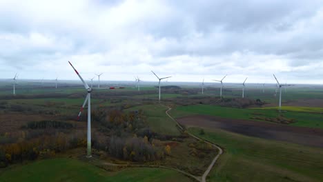 Aerial-shot-of-multiple-spinning-wind-turbines-for-renewable-electric-power-production-in-a-wide-rural-area-on-a-cloudy-day-in-4k